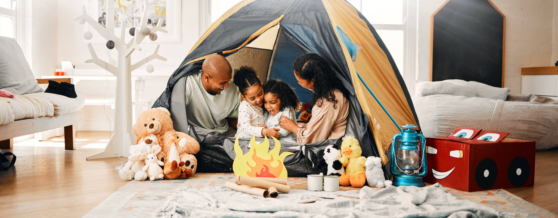 Family sitting together in a tent set up in their living room